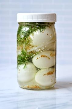 a jar filled with eggs and herbs on top of a table