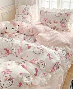 a hello kitty bed set with pink and white comforters, pillows, and stuffed animals