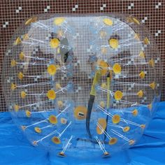 a large clear plastic object with yellow and white dots on it's face, sitting on a blue cloth