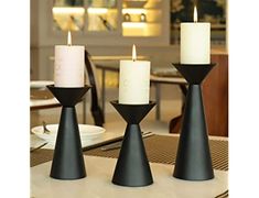 three candles sitting on top of a table next to each other in front of a dining room table