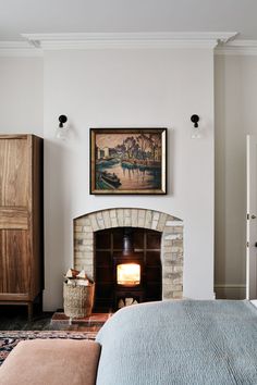 a bedroom with a bed, fireplace and painting on the wall in front of it