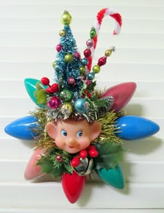 a christmas decoration hanging from the side of a wall with an elf's head on it