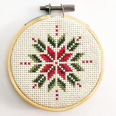 a cross stitched christmas ornament hanging from a hoop on a white wall