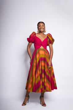 A twisted bodice accent with cutout detailing at a fixed waist seam contrasts with signature puff sleeves and a cascading rainbow midi length skirt. Raw edging and and a zipper finishing. Luxury Spring Puff Sleeve Dress With Ruched Bodice, Luxury Puff Sleeve Dress With Ruched Bodice For Spring, Puff Sleeve Trapeze Dress, Nigerian Puff Sleeve Dress, Kitenge Designs, Batik Skirt, African Fabric Dress, African Styles, Elegant Outfit Classy