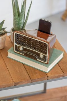 an old radio sitting on top of a wooden table next to a potted plant