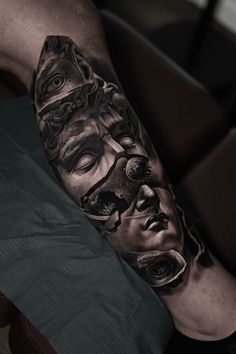 a man's arm with a black and white tattoo on it, depicting the face of