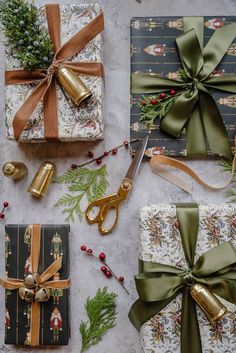 presents wrapped in wrapping paper and tied up with ribbons, pine cones, holly branches, bells, and gold scissors