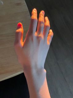 a person's hand with red nail polish on it and an orange ring in the middle