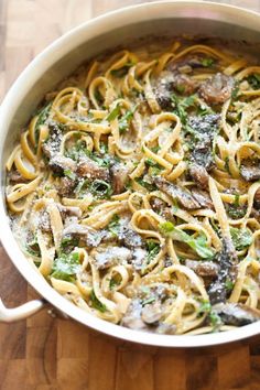 pasta with mushrooms and spinach in a pan on a wooden table, ready to be eaten