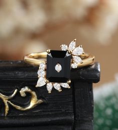 a black and white diamond ring sitting on top of a piece of wood with gold accents