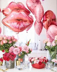 pink balloons and flowers on a table with lipstick shaped balloons in the shape of lips