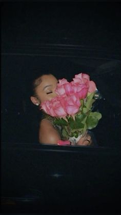 a woman holding a bouquet of pink roses