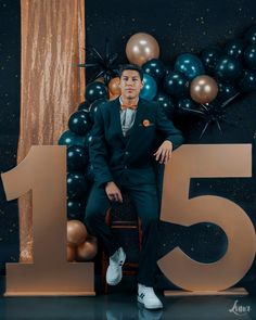 a man in a suit sitting on top of a chair next to balloons and numbers