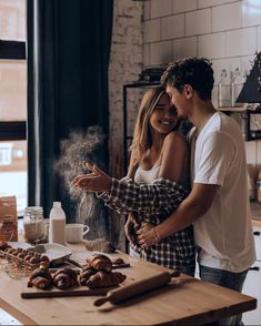 a man and woman standing in front of a table with doughnuts