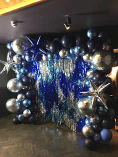 blue and silver balloons are hanging from the ceiling