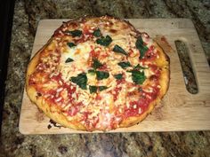 a pizza sitting on top of a wooden cutting board next to a knife and fork