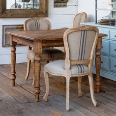 a dining room table with two chairs and a mirror on the wall above it, in front of a blue dresser