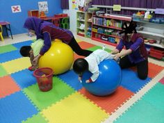 two children playing on exercise balls in a classroom