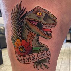 a close up of a person's leg with a dinosaur tattoo on the thigh