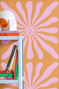 a book shelf with books on it next to a wall painted in orange and pink