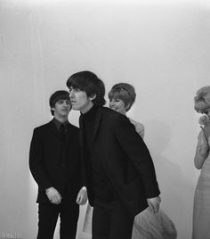 black and white photograph of three people standing next to each other in front of a wall