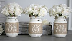 three mason jars with white flowers in them