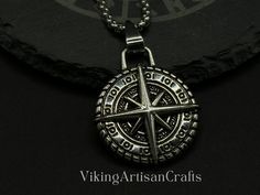 a necklace with a compass on it and the words viking arts crafts written in silver