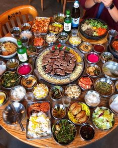 a woman sitting at a table covered in lots of food and condiments on it