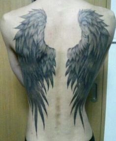 the back of a man with black and grey wings on his upper body, tattooing