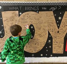 a young boy writing on a bulletin board that says joy and what brings you joy