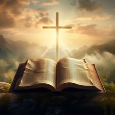 an open book with a cross on top of it in front of a mountain landscape