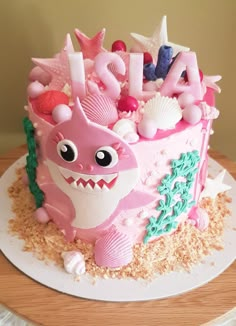 a birthday cake with pink frosting and decorations on it's side, including the number one shark