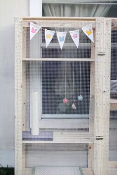 a caged in bird house with bunting and flags hanging from the window sill