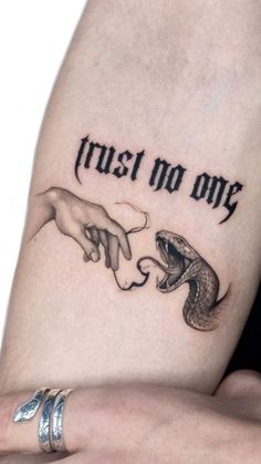 two hands touching each other with the words trust no one tattooed on their arm and wrist