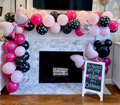 a fireplace decorated with balloons and a chalkboard sign