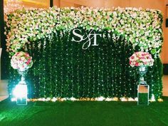 an outdoor wedding setup with white flowers and greenery on the wall, surrounded by green grass