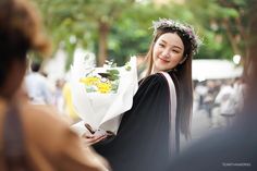 a woman in a graduation gown holding flowers