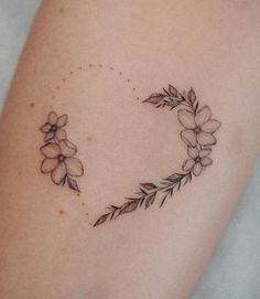 a tattoo with flowers and leaves on the back of her arm, which is shaped like a heart