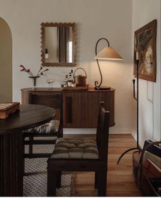 a room with a table, chair and mirror in it that has a lamp on top of it