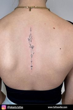 the back of a woman's shoulder with a flower tattoo on her left side