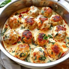 a white pot filled with meatballs covered in sauce and garnished with herbs