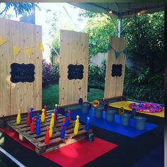 an outdoor play area with wooden doors and chalkboards on the walls, painted blue, yellow and red