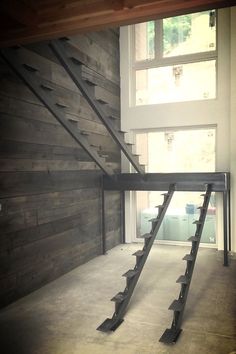 an empty room with wooden walls and metal railings on the bottom floor, leading to a second story window