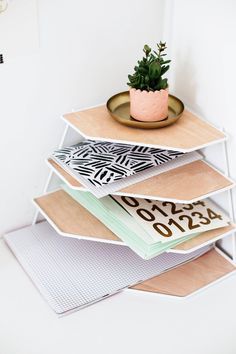 a stack of books with a potted plant sitting on top of one book shelf