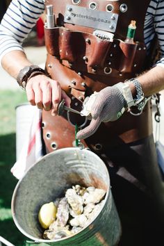 a man in an apron is pouring something into a bucket with oysters on it