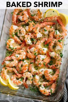 a glass dish filled with shrimp and garnished with parsley, lemon wedges