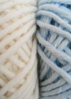 two skeins of white and blue yarn are close together in this image, one is slightly blurry