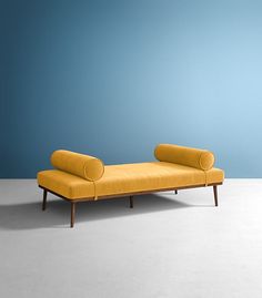 a yellow couch sitting on top of a white floor next to a blue wall in an empty room