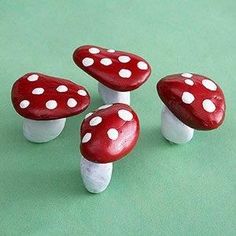 three red and white mushrooms sitting on top of a green surface