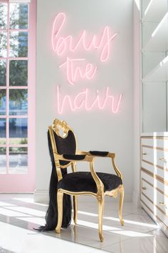 a chair with long black hair sitting in front of a neon sign that reads beauty the heart